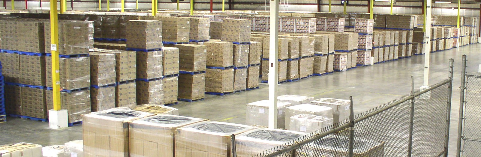 pallets of boxes wrapped in plastic in rows in warehouse