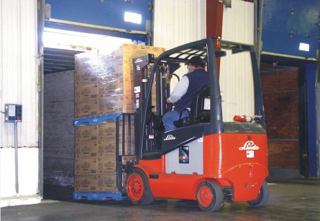 Man in forklift driving pallet of boxes into back of transport truck