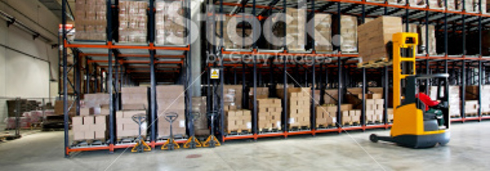 Shelves of product and forklift lifting pallet off of second shelf