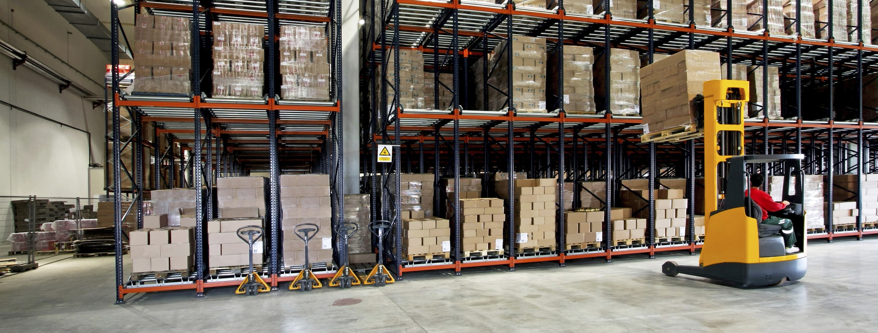 Yellow fork lifter work to remove boxes off shelf in big warehouse